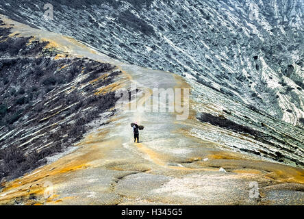Un minatore di zolfo passeggiate sul Monte Ijen ridge. Java Orientale, Indonesia. Foto Stock
