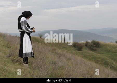 Donna vestito in abiti tradizionali sta leggendo un libro sulla cima di una collina nel centro di Transilvania Foto Stock