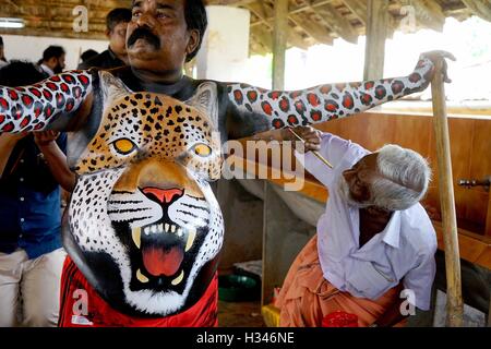 Un ballerino qualificato ottiene il suo corpo verniciato nei colori di una tigre si prepara a partecipare famoso Pulikali Thrissur Kerala Foto Stock