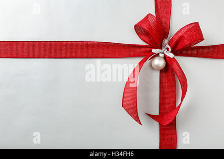 Regalo di Natale regalo di Natale sfondo con argento carta di avvolgimento e fiocco rosso Foto Stock