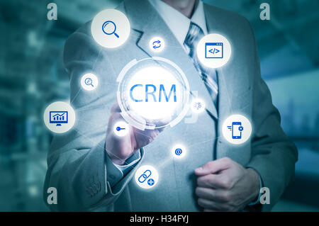 Business, tecnologia internet e customer relationship management concetto. Imprenditore premendo il pulsante crm su schermi virtuali Foto Stock