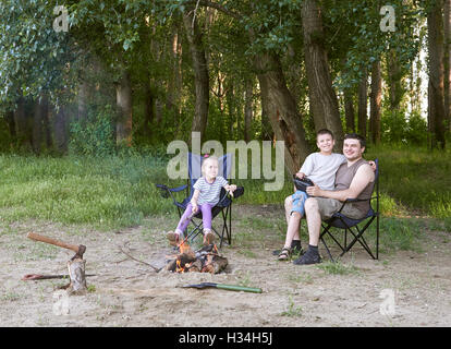 Persone campeggio in foresta, famiglia attiva in natura, Kindle fuoco, durante la stagione estiva Foto Stock