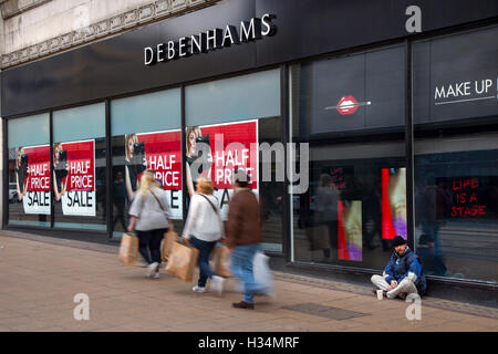 Fuori fuoco sfocato shoppers, gente camminare figure passando a metà prezzo vendita autunnale segni in negozio Debenhams, Manchester, Regno Unito. Vendita e riduzioni, offerte & offerte, articoli in liquidazione, sconto, Prezzo, Promozione, retail business in negozio Debenhams. Foto Stock