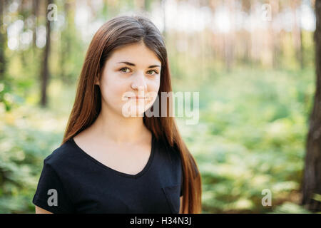 Close up ritratto di Felice i Capelli rossi ragazza caucasica giovane donna in estate foresta verde. Ragazza vestita in una T-shirt nera. Essere umano Foto Stock