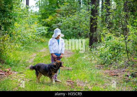 Felice bambina giocando con il cane nella foresta Foto Stock