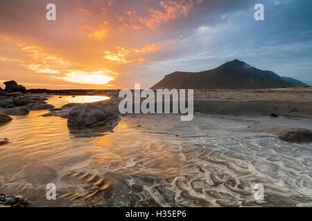 Il sole di mezzanotte si riflette sulla spiaggia di sabbia di Skagsanden, Ramberg, Nordland county, Isole Lofoten artico, Norvegia Foto Stock