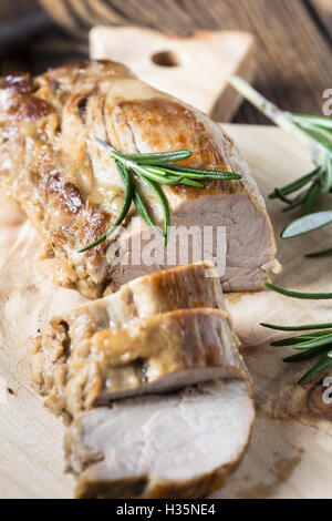 Deliziosi arrosti di filetto di maiale con il rosmarino sulla tavola di legno Foto Stock