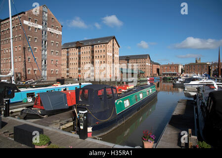 Gloucester Docks Gloucestershire England Regno Unito. Narrowboats ormeggiato con uno sfondo di rifornire i magazzini nella vecchia zona del dock Foto Stock