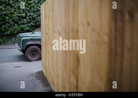 Un vecchio green land rover nascosto dietro un grande recinto di botte. Foto Stock