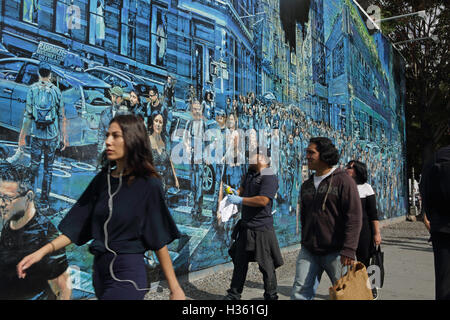 NYC pedoni a piedi passato un grande murale dipinto da Logan Hicks sulla Bowery parete murale, Houston Street Foto Stock