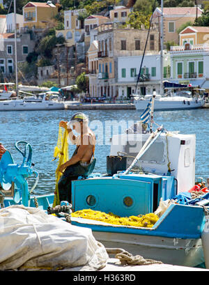 Pescatore con la barca e le reti di città Symi Grecia Foto Stock