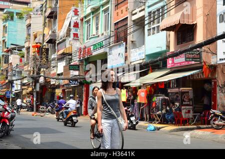 Donna sulla strada di Saigon (Ho Chi Min City) piena di fili. Foto Stock