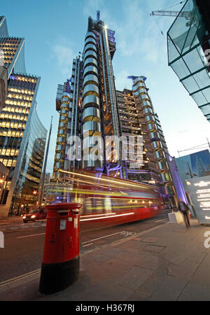 Red London bus passa Lloyd's edificio al crepuscolo, calce St, Inghilterra Foto Stock