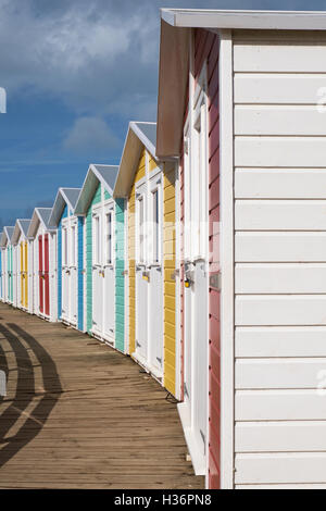 Fila di chalets bloccata fuori stagione e costruito nello stile di quelle che si trovano tradizionalmente in inglese mare Foto Stock