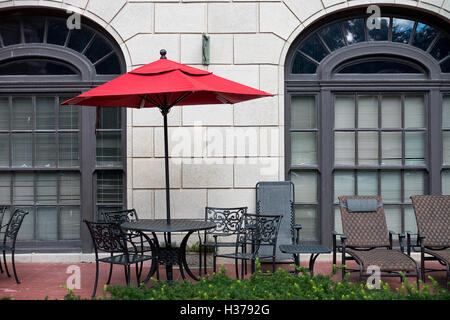 L'ombrellone rosso sul patio con tavolo e sedie Foto Stock