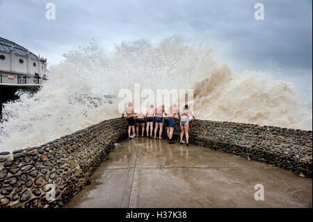 I membri del gruppo Brighton Nuoto Club godono di un 'groyne doccia' quando il mare è troppo pericolosa per nuotare. Foto Stock