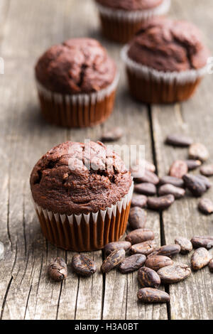 Il gustoso muffin al cioccolato e cacao in grani sul vecchio tavolo in legno. Foto Stock