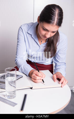 Giovane professionista sta scrivendo la sua idea di aprire il notebook Foto Stock