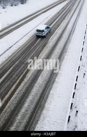 Una vista della A419 / A417 by pass la coperta di neve con i veicoli che viaggiano molto lentamente nella pericolosa condizioni stradali, nella foto dopo un pesante nevicata invernale la strada che teste attraverso il cuore di Cotswolds nel Regno Unito è a malapena praticabile in questi unusally cattive condizioni per viaggiare. Foto Stock