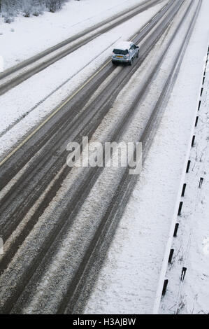 Una vista della A419 / A417 by pass la coperta di neve con i veicoli che viaggiano molto lentamente nella pericolosa condizioni stradali, nella foto dopo un pesante nevicata invernale la strada che teste attraverso il cuore di Cotswolds nel Regno Unito è a malapena praticabile in questi unusally cattive condizioni per viaggiare. Foto Stock