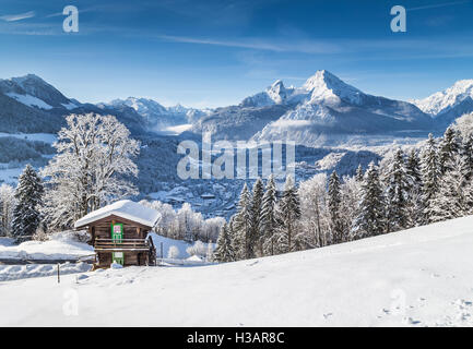 Winter Wonderland paesaggio di montagna delle Alpi con chalet di montagna tradizionale su una bella fredda giornata soleggiata con cielo blu Foto Stock