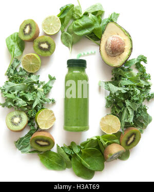 Imbottigliato frullato verde circondato con frutta e verdura compresi gli spinaci kale e avocado Foto Stock