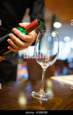 Cameriere versando il vino rosso in vetro Foto Stock