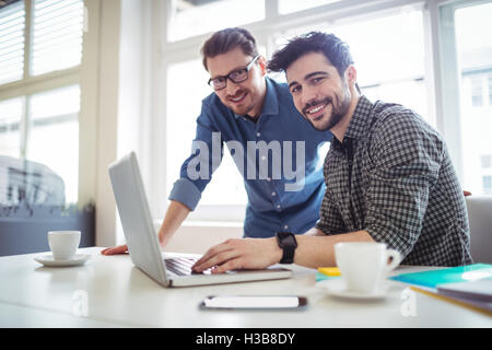 Ritratto di sorridente editor di foto utilizzando laptop Foto Stock