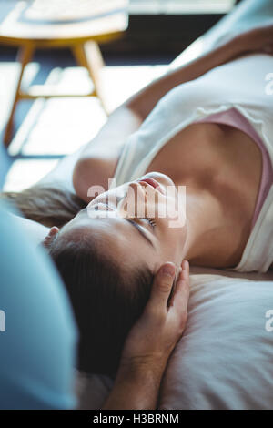 Fisioterapista maschio dando massaggio della testa al paziente di sesso femminile Foto Stock