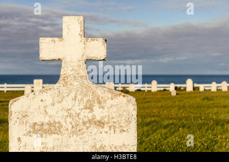 Lapide vuota in un cimitero, con l'oceano sullo sfondo, al tramonto Foto Stock