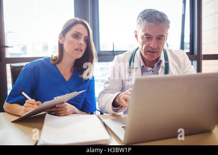 Medico per discutere con un infermiere su laptop Foto Stock