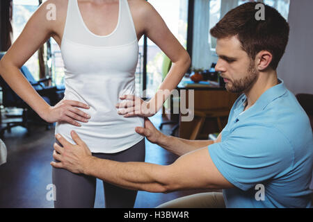 Fisioterapista di correggere la posizione del paziente femmina Foto Stock