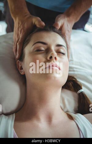Fisioterapista maschio dando massaggio della testa al paziente di sesso femminile Foto Stock