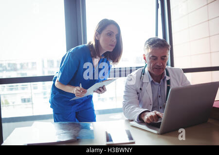 Medico per discutere con un infermiere su laptop Foto Stock