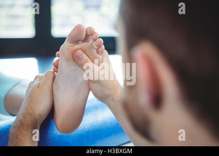 Fisioterapista maschio dando massaggio ai piedi per il paziente di sesso femminile Foto Stock