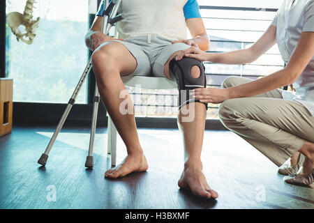 Fisioterapista femmina esaminando il suo ginocchio del paziente Foto Stock