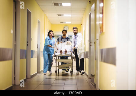 Medico e infermiere spingendo un senior del paziente sul lettino Foto Stock