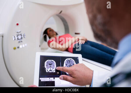 Medico guardando il cervello MRI scan su tavoletta digitale Foto Stock