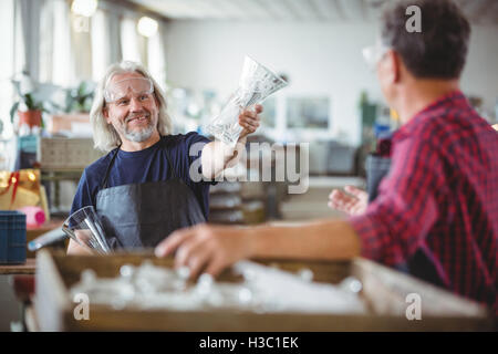 Glassblower mostra vaso di vetro a un collega Foto Stock