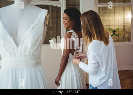 Donna cercando in abito da sposa con il contributo di designer di moda Foto Stock