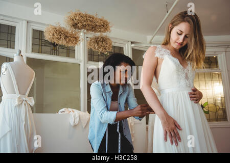 Donna cercando in abito da sposa con il contributo di designer di moda Foto Stock