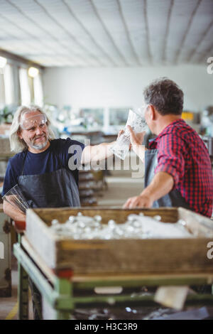 Glassblower mostra vaso di vetro a un collega Foto Stock