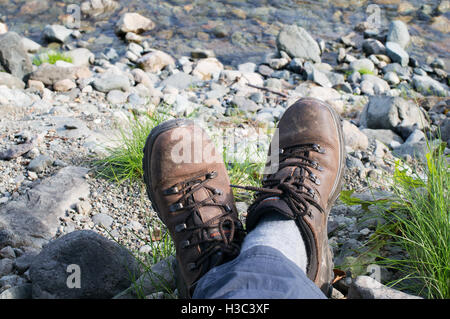 Piedi e stivali di walker in appoggio vicino torrente nel Lake District Inghilterra, Regno Unito Foto Stock