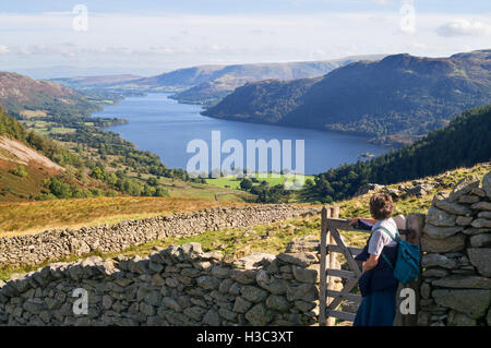 Il camminatore femmina al cancello guardando verso Ullswater da Glencoyne sulla salita di Sheffield Pike, Cumbria, England, Regno Unito Foto Stock