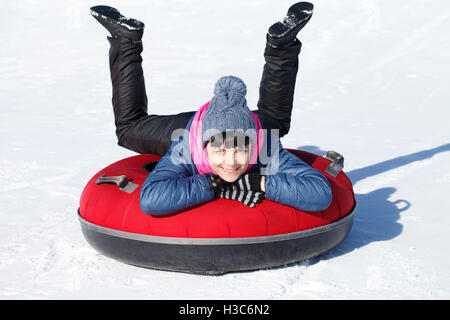 Giovane ragazza allegra passa per una trasmissione su un tubo di neve, in inverno, divertente, umorismo Foto Stock