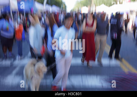 Sfumata la folla di gente che cammina verso il basso una fiera di strada di New York City. Disegno astratto concetto. Nella fotocamera fuori fuoco effetto. Foto Stock