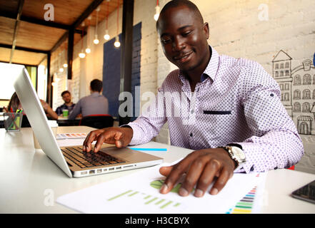 Immagine dell'African American businessman lavorando sul suo computer portatile. Bel giovane uomo alla sua scrivania Foto Stock