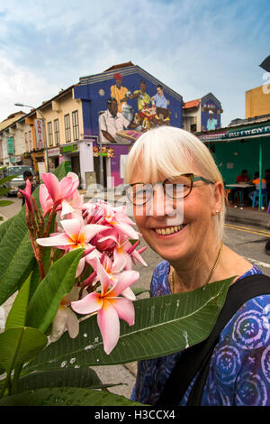 Singapore, Little India, Belilios Lane, turistico guardando rosso fiori di frangipani sulla struttura fragrante Foto Stock