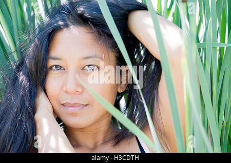 Donna tra le fronde con le mani nei capelli, ritratto Foto Stock