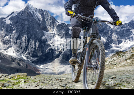 Mountain bike rider con protezioni cavalca un single trail in grande altezza. Lo sfondo mostra "L' Ortles montagna del massiccio Foto Stock